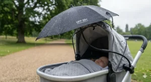 A compact black pushchair parasol folded neatly and stored in an under-seat shopping basket.