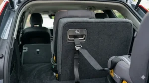 Alt text for image 6: A detailed photorealistic shot showing a black car seat top tether strap and hook secured to a metal anchor bar integrated into the rear seat-back of a modern car.