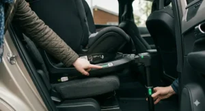 Detailed shot of a rotating car seat base with glowing green safety indicators confirming secure ISOFIX attachment and support leg positioning.