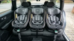 Alt text for image 5: Photorealistic high-angle shot looking down into a large UK family car, showing three i-size compatible car seats securely fitted side-by-side across the rear bench.