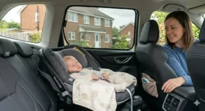 A peaceful baby sleeping in a car seat shielded from harsh glare by a fitted car window sunshade for baby.