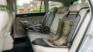 Durable rear seat protector mat catching thick mud and grime from a folded pushchair chassis and a pair of green rubber wellington boots.