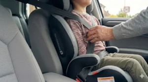 A deflated inflatable travel booster seat shown next to a hand to demonstrate its compact, pocket-sized design.