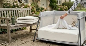 A baby sleeping soundly in a safe, lightweight travel cot with breathable mesh sides.