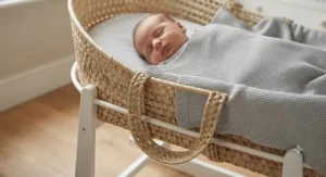 A peaceful newborn baby sleeping soundly in a natural wicker moses basket set.