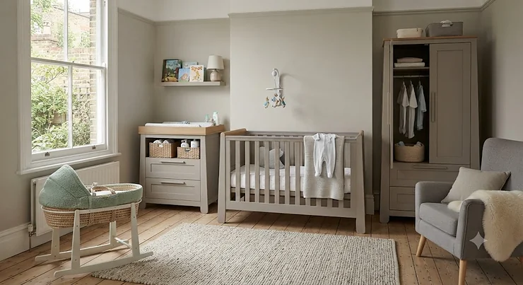 A complete traditional nursery furniture set including a solid wood cot bed, matching wardrobe, and chest of drawers with a changing table top, styled in a classic British home interior. traditional nursery furniture set