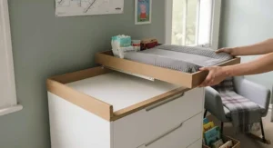 Close-up view of the deep drawers on a nursery changing dresser open to reveal organised baby clothes, muslins, and changing essentials.