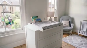 Lightweight standalone changing table positioned flexibly next to a cot in a UK baby's room.